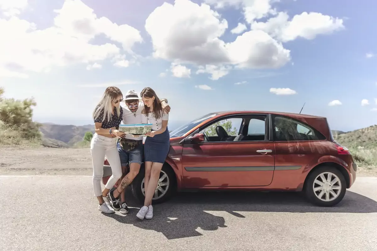 Friends checking a map beside their hire car on a road in Andalusia